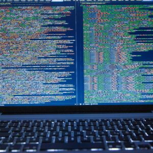 Laptop displaying source code with dual screens for software development.